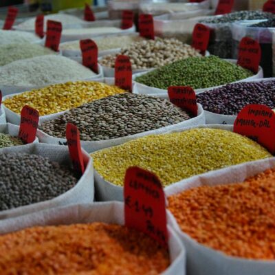 Bags of vibrant grains and spices on display in a bustling market setting.