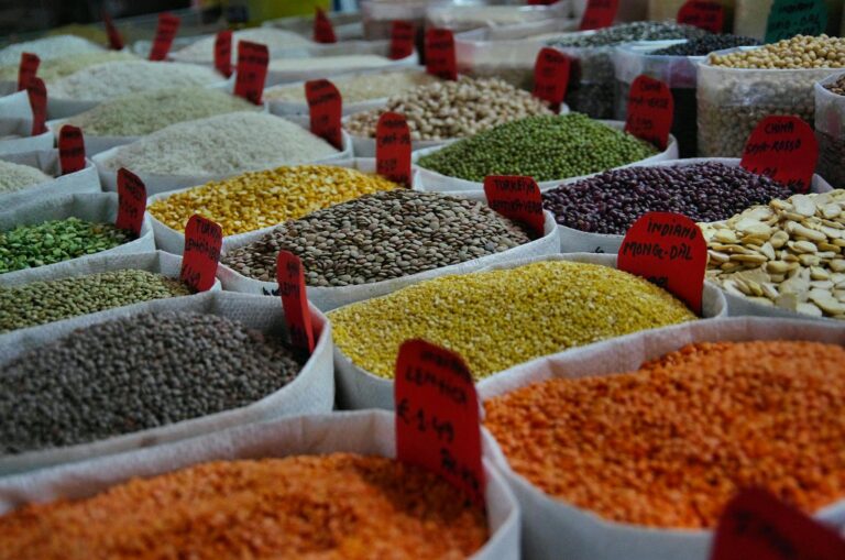 Bags of vibrant grains and spices on display in a bustling market setting.