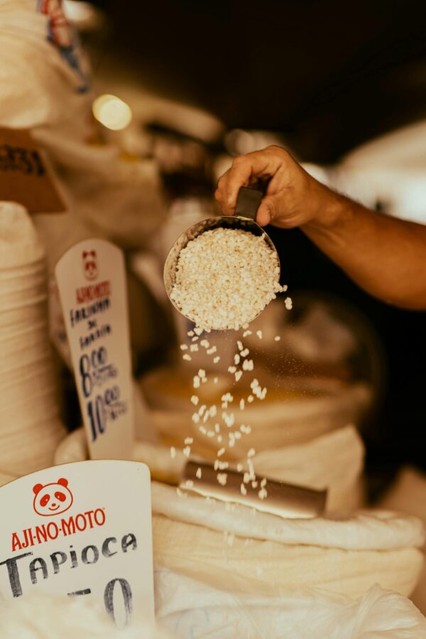 Close-up of hand scooping tapioca at a market. Perfect for food and culture themes.