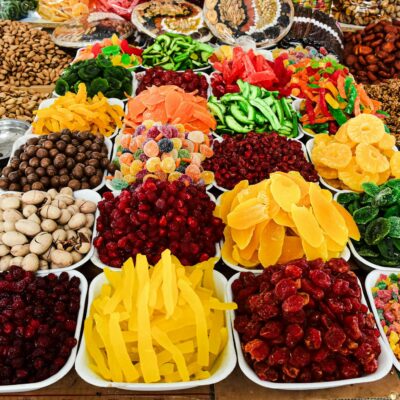 Colorful assortment of dried fruits and nuts on display at a market stall, showcasing a variety of textures and colors.