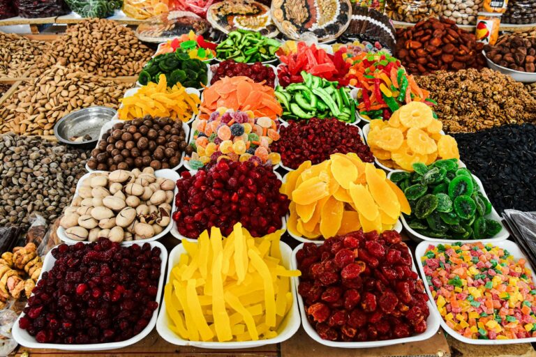 Colorful assortment of dried fruits and nuts on display at a market stall, showcasing a variety of textures and colors.